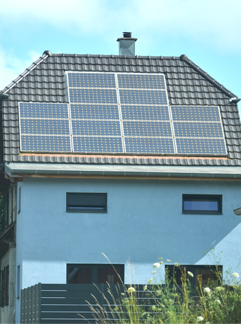 Einfamilienhaus mit Photovoltaikanlage auf einem geneigten Ziegeldach.